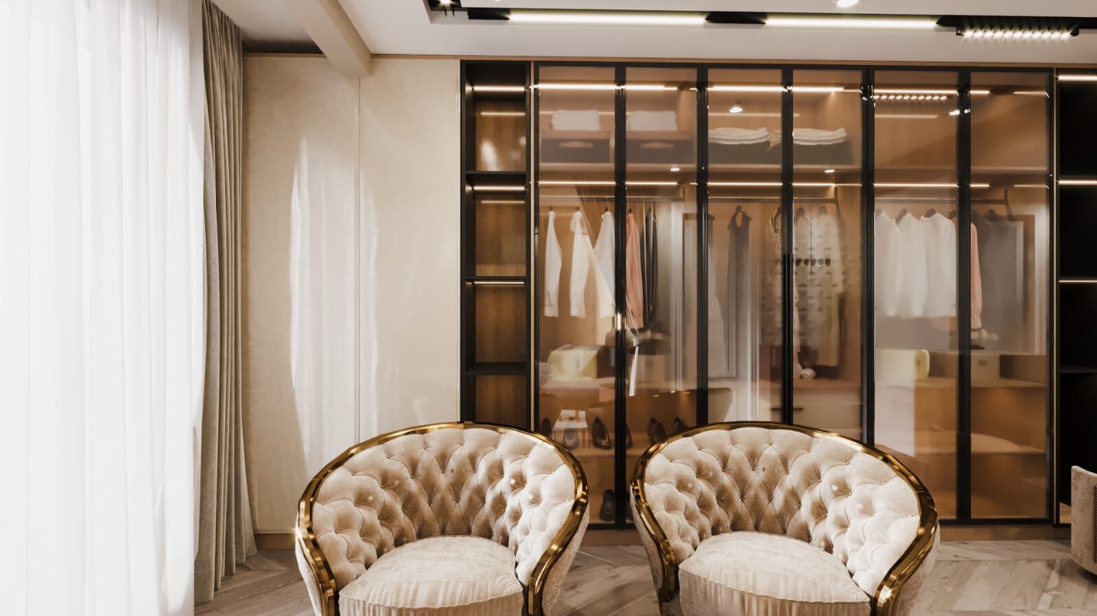 A seating corner off the dressing room: two gold-framed tufted
                  chairs facing a glass-fronted wardrobe lit from within, with a
                  sheer curtain drawn across the daylight to one side.