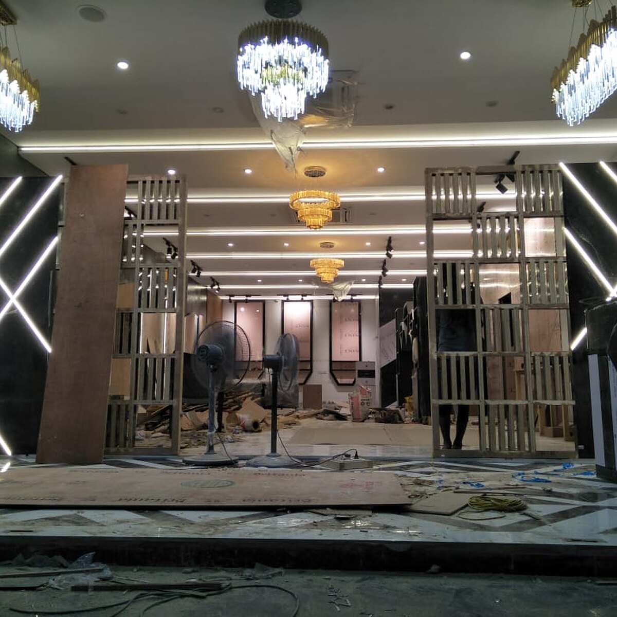 The FTV Salon threshold: white neon chevrons across black marble beside a brass fin screen.