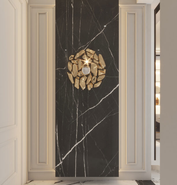 A black marble panel between fluted cream pilasters, lit by a brass sunburst fitting.