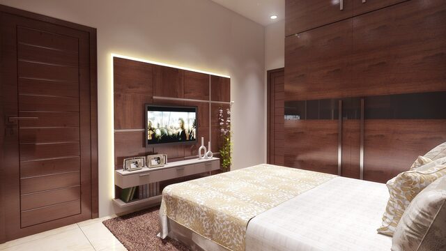 A bedroom wall in ribbed dark timber, carrying the television above a low run of drawers.