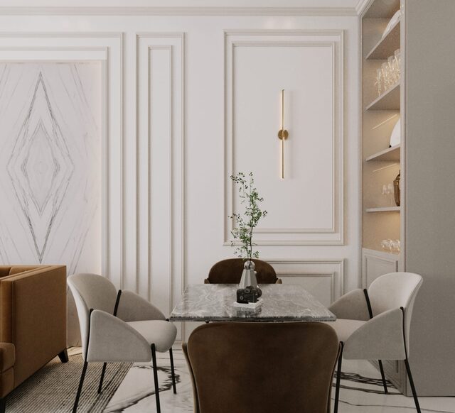 A panelled dining room in cream and marble, a round table with tan leather and pale chairs.