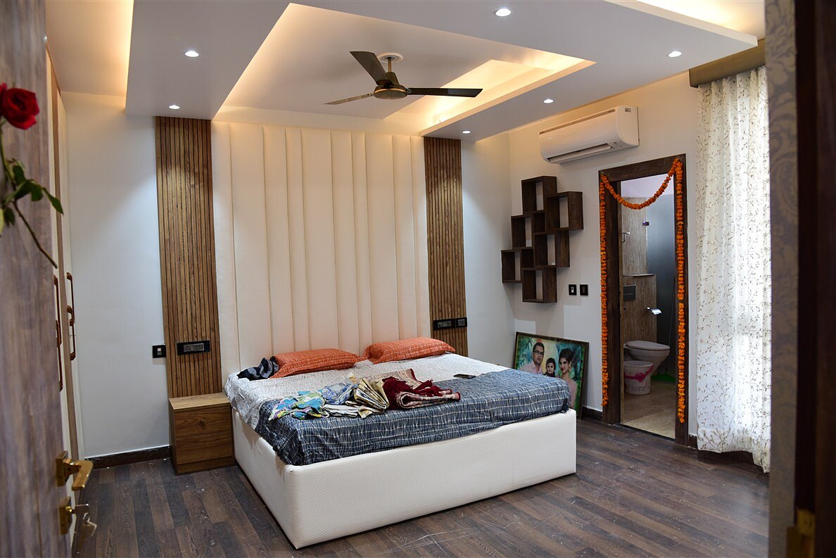 A second bedroom as built, timber panelling behind the bed under a lit cove.