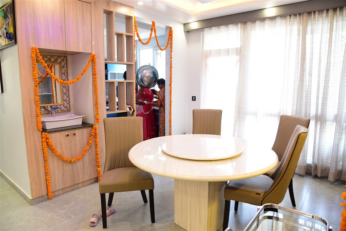The dining room as built, a round timber table beside the crockery unit, garlanded for the housewarming.