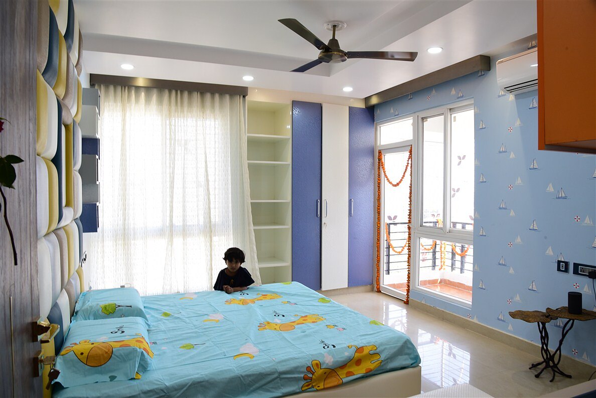 A child's room as built, in blue with printed curtains and open shelving.