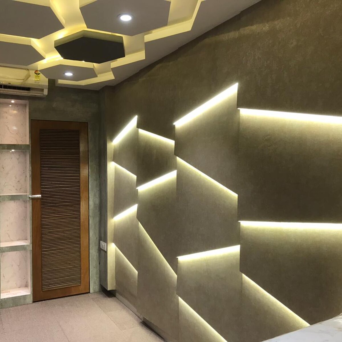 The real estate office: a faceted feature wall lit from within, under hexagonal ceiling coffers.
