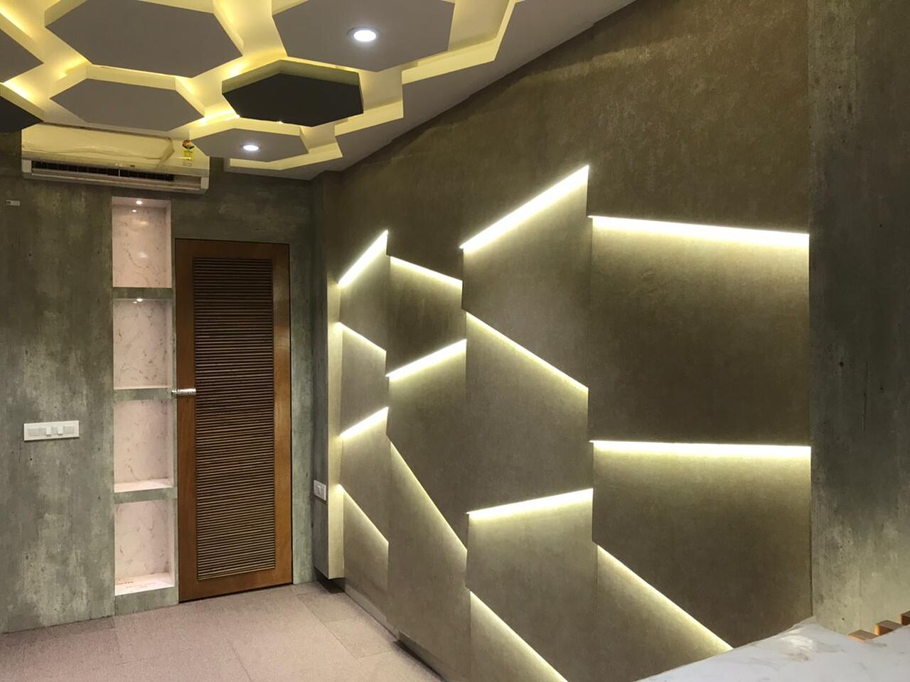 The faceted feature wall as built: stepped planes each lit from within, beneath a ceiling of hexagonal coffers.
