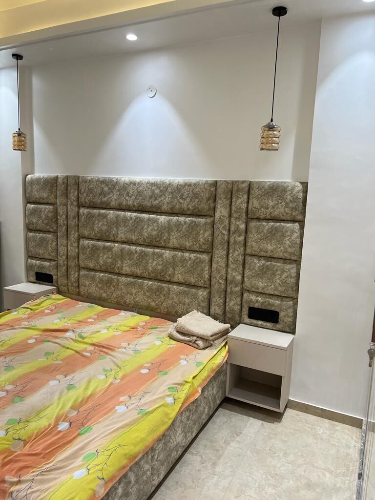 A bedroom: a wide channelled headboard running the width of the bed,
                  with a built-in bedside shelf and a pendant hung either side.