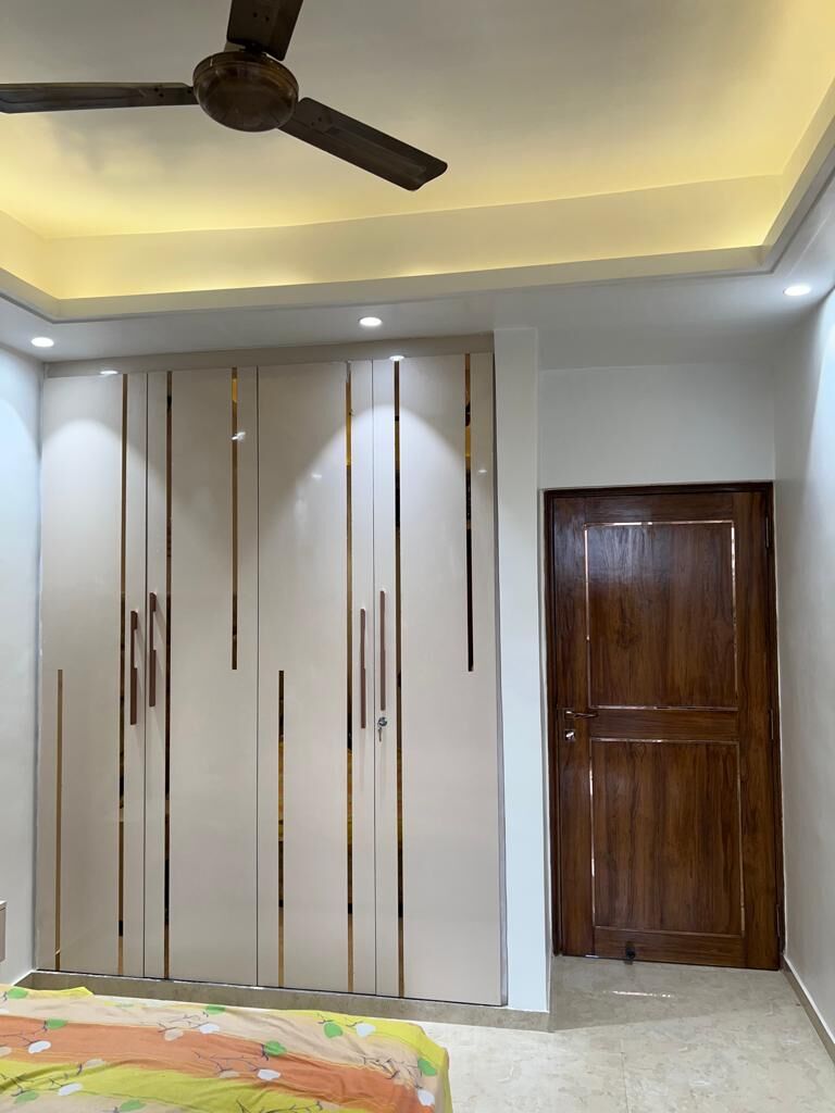 A bedroom wardrobe run: full-height doors with slim vertical handles, a
                  timber door beside them and a cove-lit ceiling above.