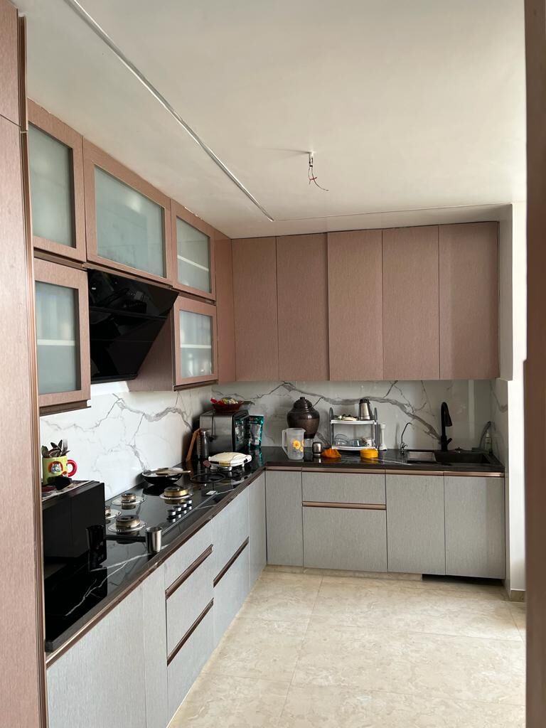 The kitchen: blush upper cabinets over pale grey bases, a marble
                  splashback and a dark stone counter running to the window.